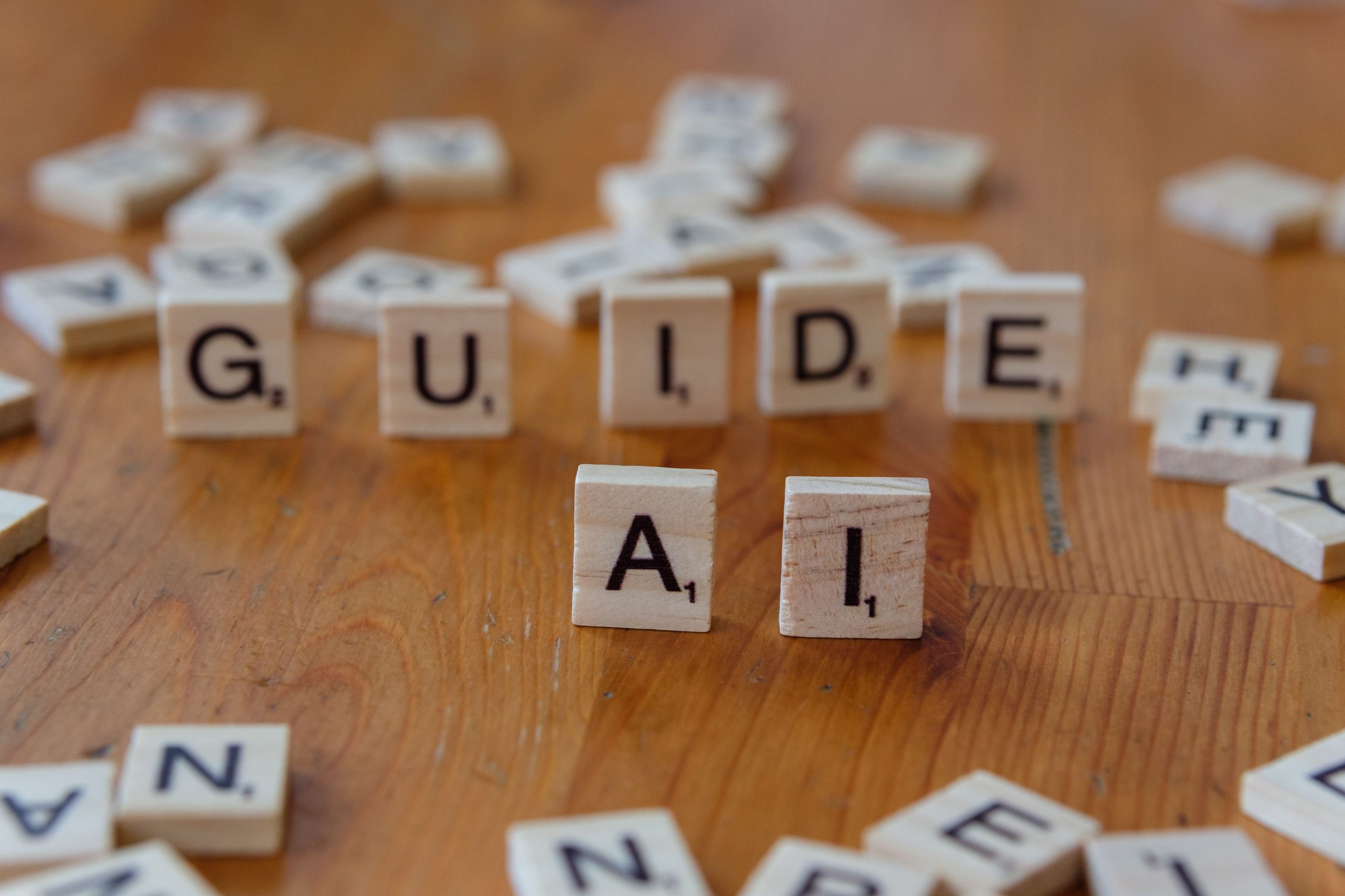 Tuiles de scrabble formant les mots 'GUIDE' et 'IA' sur un fond en bois.